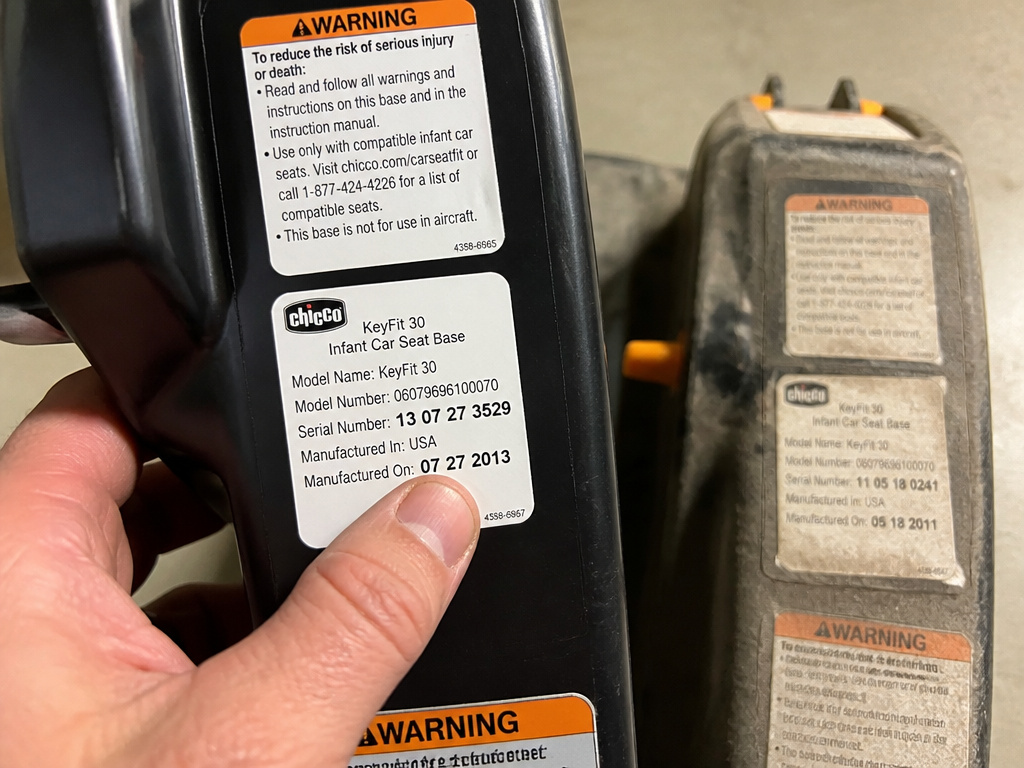 Close-up of a car seat base manufacture date label next to a faded older base.